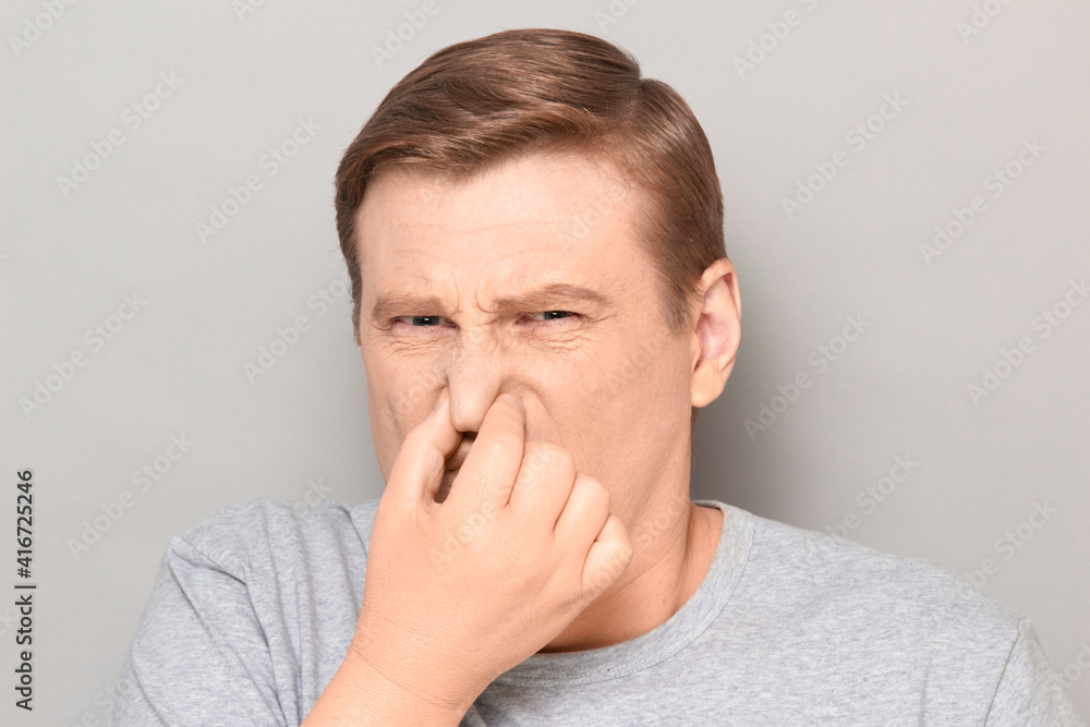 Portrait of mature man pinching his nose and grimacing from disgust Portrait of mature man pinching his nose and grimacing from disgust