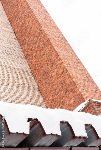 a chimney  part of wall and part of roof covered by snow