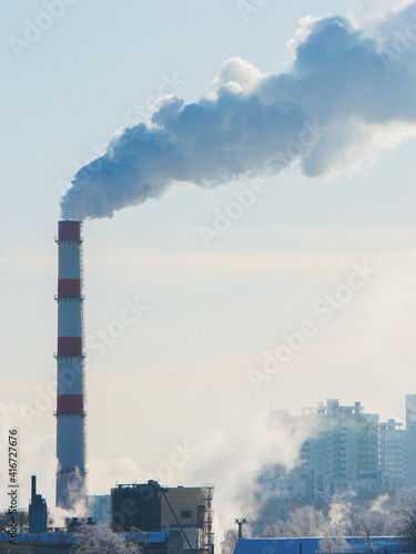 chimney with thick smoke against a background of light blue sky.