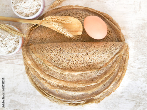 Photos Top view of traditional French region of savory crepes Buckwheat Galettes Bretonnes with flour, wheat plant and egg on a wooden table