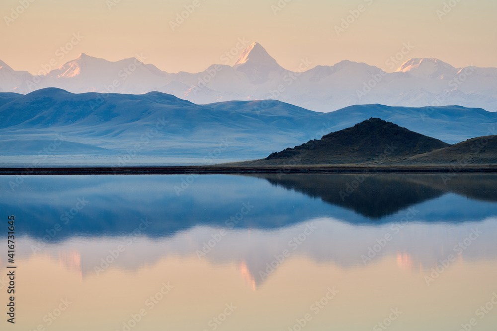 Lake Tuzkol in Kazakhstan and a view of Khan Tengri peak at sunrise reflection of a mountain peak in the lake.