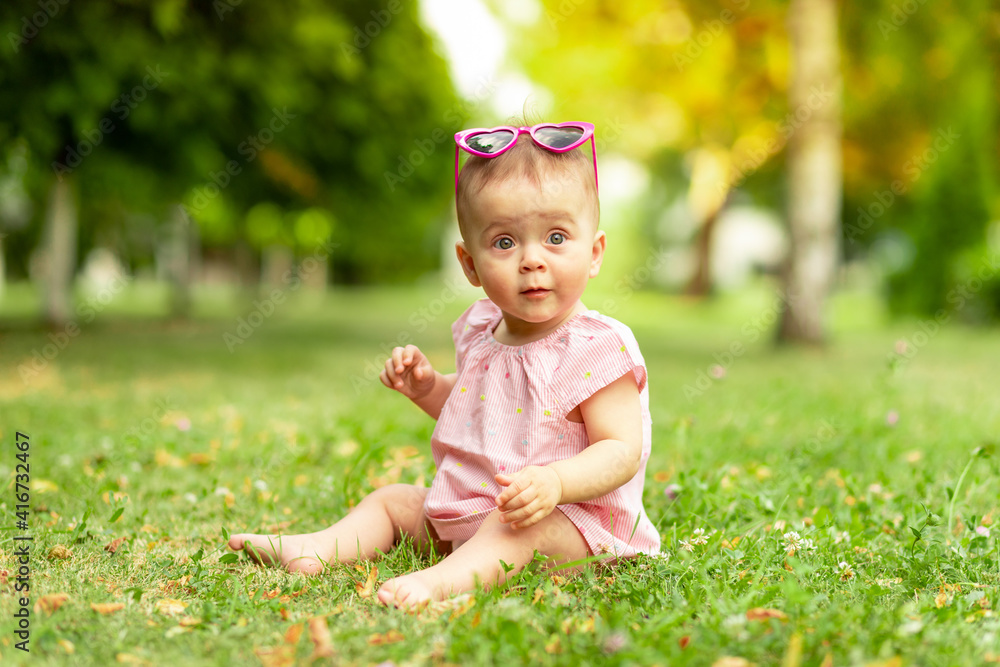 baby wearing sunglasses on the lawn or grass in summer, baby walking in the fresh air baby wearing sunglasses on the lawn or grass in summer, baby walking in the fresh air