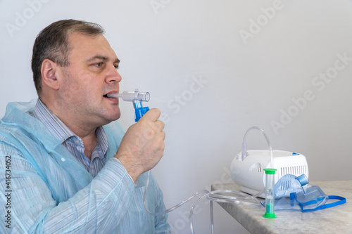man holds a breathing tube and inhales. nebulizer and Oxygen Mask. spraying of a drug that is delivered to the patient through a mask or breathing tube. treatment of respiratory diseases and allergies