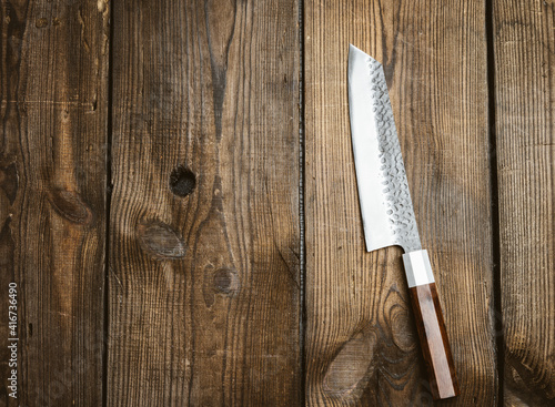 metal kitchen knife on a table made of brown wooden boards, top view