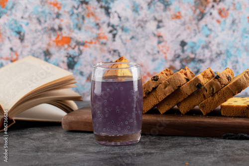 Close up photo of fresh grape cocktail with sliced cake and book