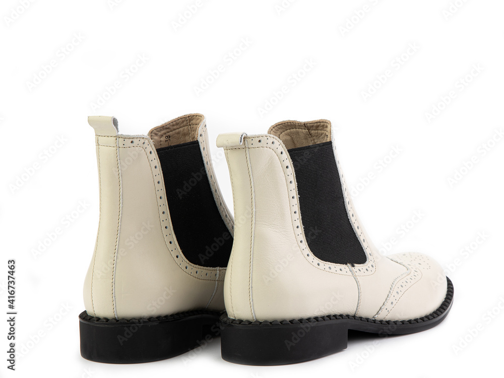 White leather chelsea boots with black elasticated side details, pattern details and black rubber sole. Isolated close-up on white background. Back side view. Fashion shoes.