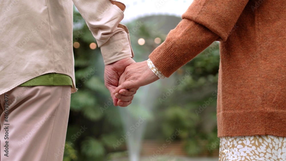 An old couple are holding hands