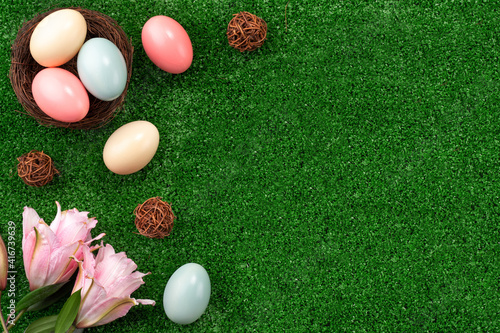 Colorful Easter eggs in the nest on a lawn with pink Double Lily flower.