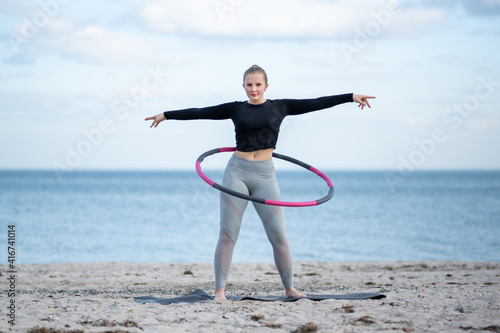 Junge sportliche Frau trainiert mit Hula Hoop im Freien am Strand für einen gesunde Lebensstil, Konzept photo