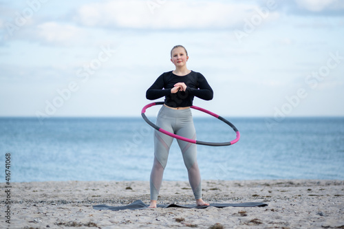 Junge sportliche Frau trainiert mit Hula Hoop im Freien am Strand für einen gesunde Lebensstil, Konzept