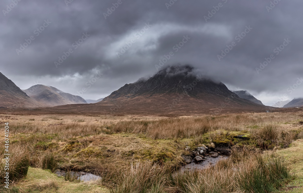 Stunning majestic landscape image of Buachaille Etive Mor and River Etive in Scottish Highlands on a Winter morning with moody sky and lighting