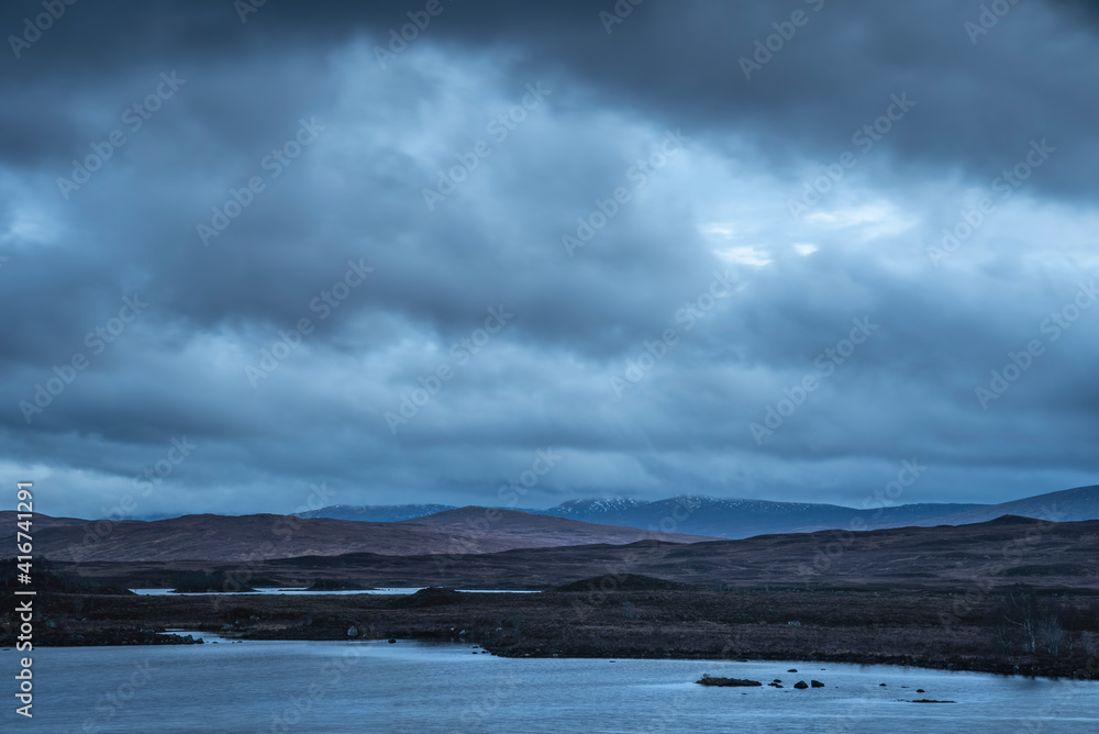 Epic dramatic landscape image of Loch Ba on Rannoch Moor in Scottish Highlands on a Winter morning