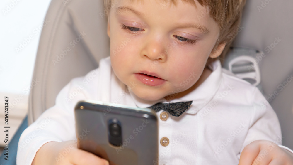 A curious child is watching an interesting video on the phone. Modern gadgets in the hands of a child. Carefree childhood A curious child is watching an interesting video on the phone. Modern gadgets in the hands of a child. Carefree childhood