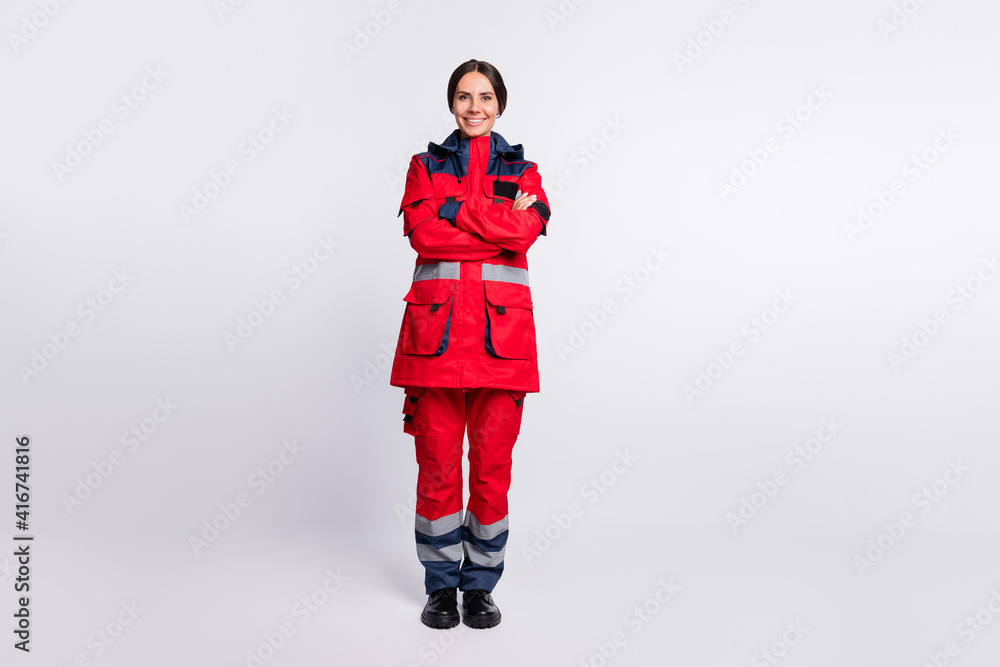Full length photo of good mood young ambulance lady dressed red uniform hands folded smiling isolated white color background Full length photo of good mood young ambulance lady dressed red uniform hands folded smiling isolated white color background