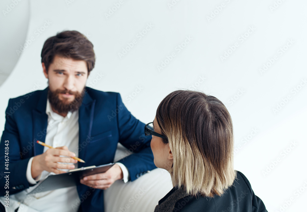 Business man with documents explains something to a young woman Sitting on a sofa indoors Business man with documents explains something to a young woman Sitting on a sofa indoors