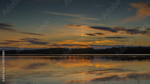 Beautiful sunset landscape over a Finnish lake. The space is flooded with gold.