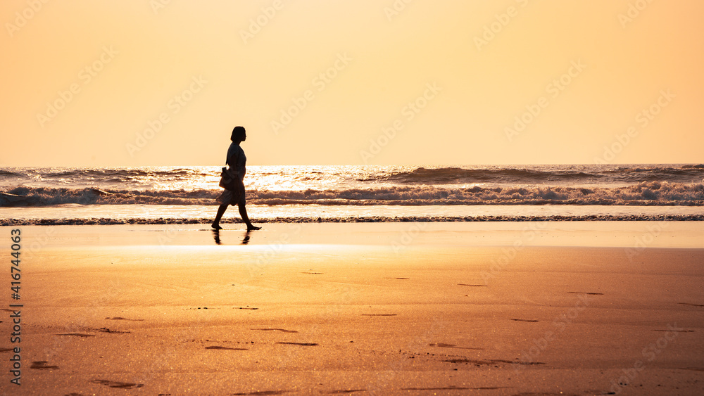 Silhouette of a lady walking on the beach