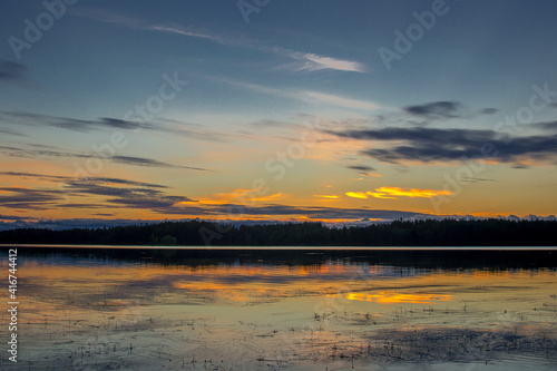 Beautiful sunset landscape over a Finnish lake. The space is flooded with gold.