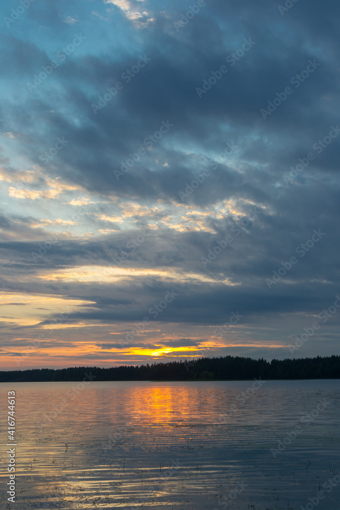 Beautiful sunset landscape over a Finnish lake. The space is flooded with gold.