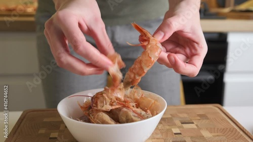 Woman cleaning shrimps for cooking. Process of hands peel shrimps shell photo
