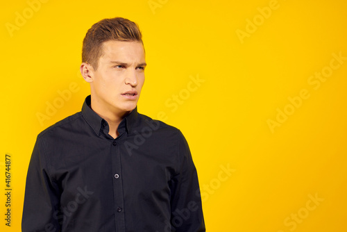 business man in black shirt studio cropped view yellow background