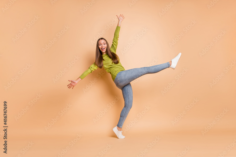 Fototapeta premium Full length photo of lady dance raise hands leg wear green pullover footwear jeans isolated beige color background