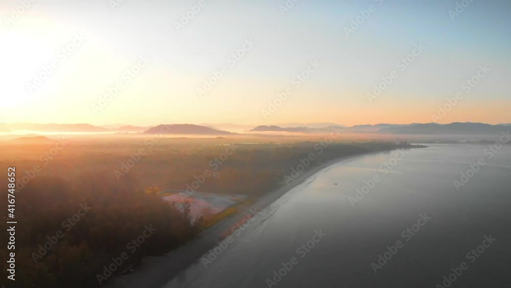 Aerial view of drone fly backward over tropical beach with pastel golden hour sky during sunrise Koh Kho Khao, Khao Lak, Phang Nga, Thailand. Aerial view of drone fly backward over tropical beach with pastel golden hour sky during sunrise Koh Kho Khao, Khao Lak, Phang Nga, Thailand.