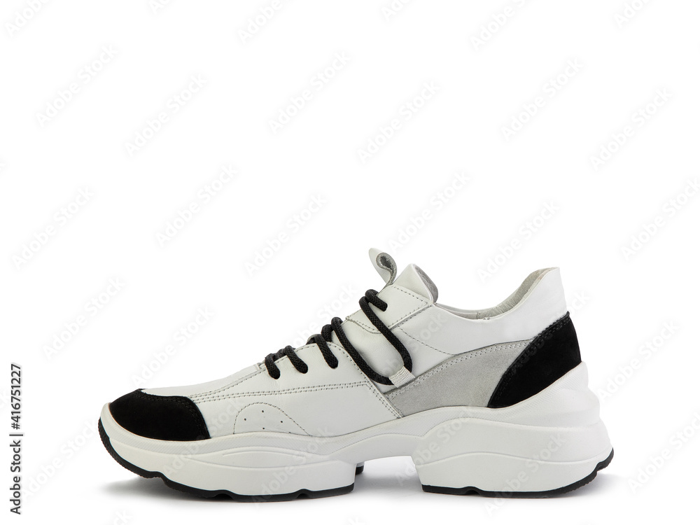 Stylish white women trainers with black and grey suede details. Black lacing and white and black rubber soles. Isolated close-up on white background. Left side view. Casual women's style. Stylish white women trainers with black and grey suede details. Black lacing and white and black rubber soles. Isolated close-up on white background. Left side view. Casual women's style.