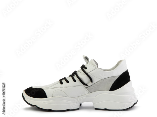 Stylish white women trainers with black and grey suede details. Black lacing and white and black rubber soles. Isolated close-up on white background. Left side view. Casual women's style.