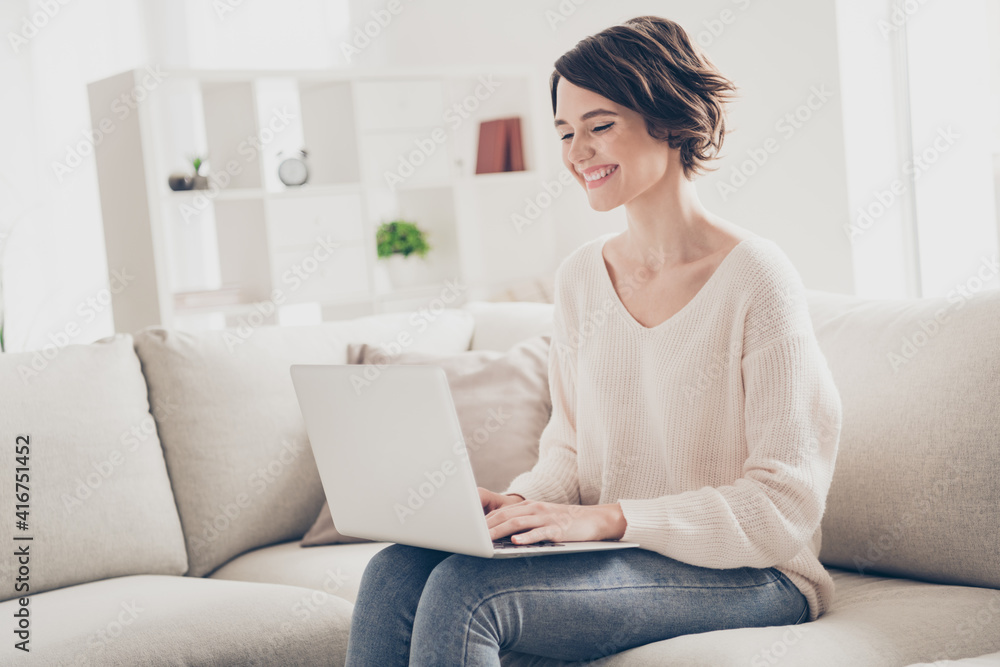 Profile side photo of happy bob haired woman hold laptop sit sofa smile good mood inside house indoors Profile side photo of happy bob haired woman hold laptop sit sofa smile good mood inside house indoors