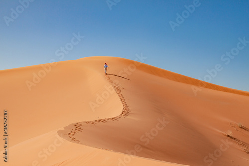 girl climbs a dune in the desert  