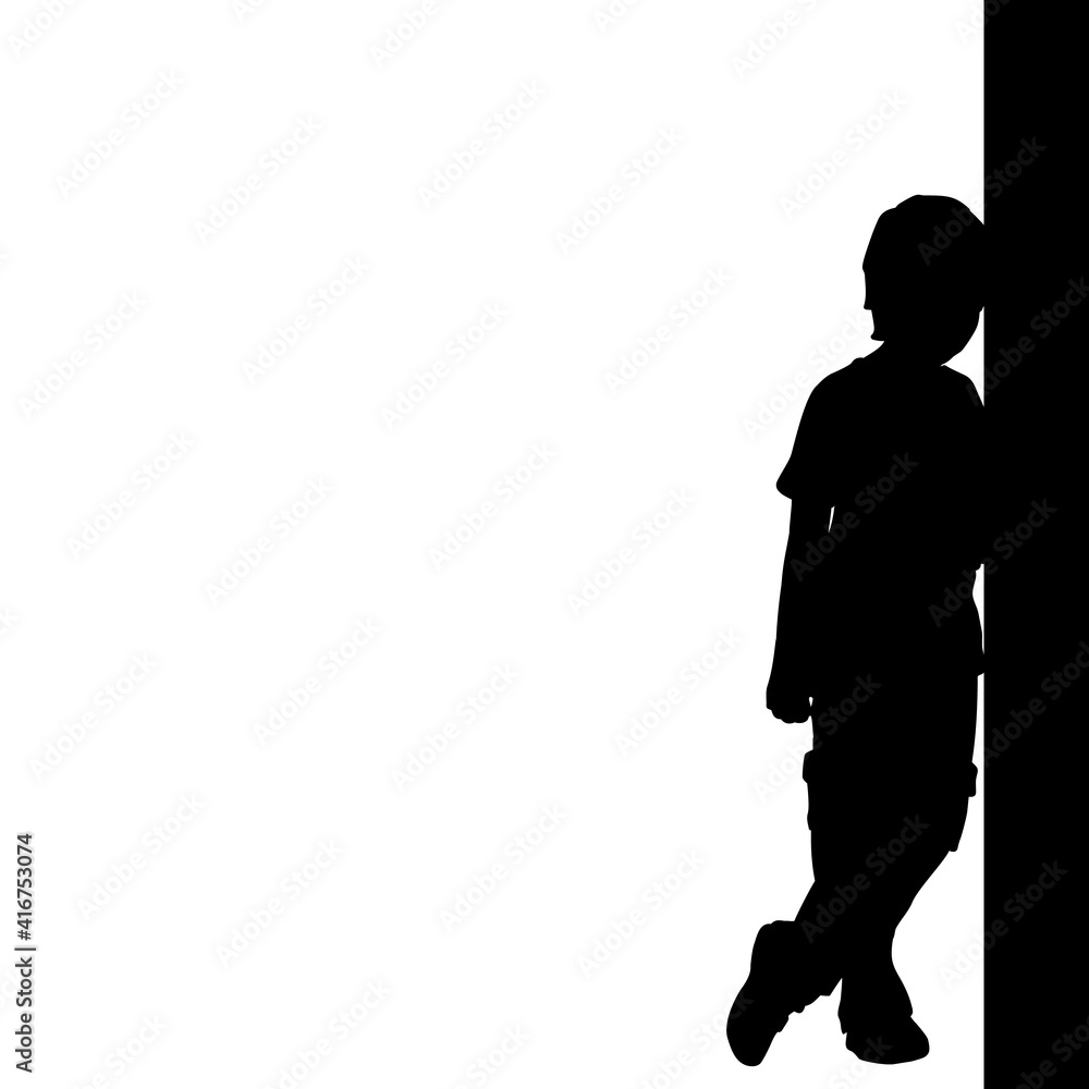 Silhouette of boy standing by the wall.