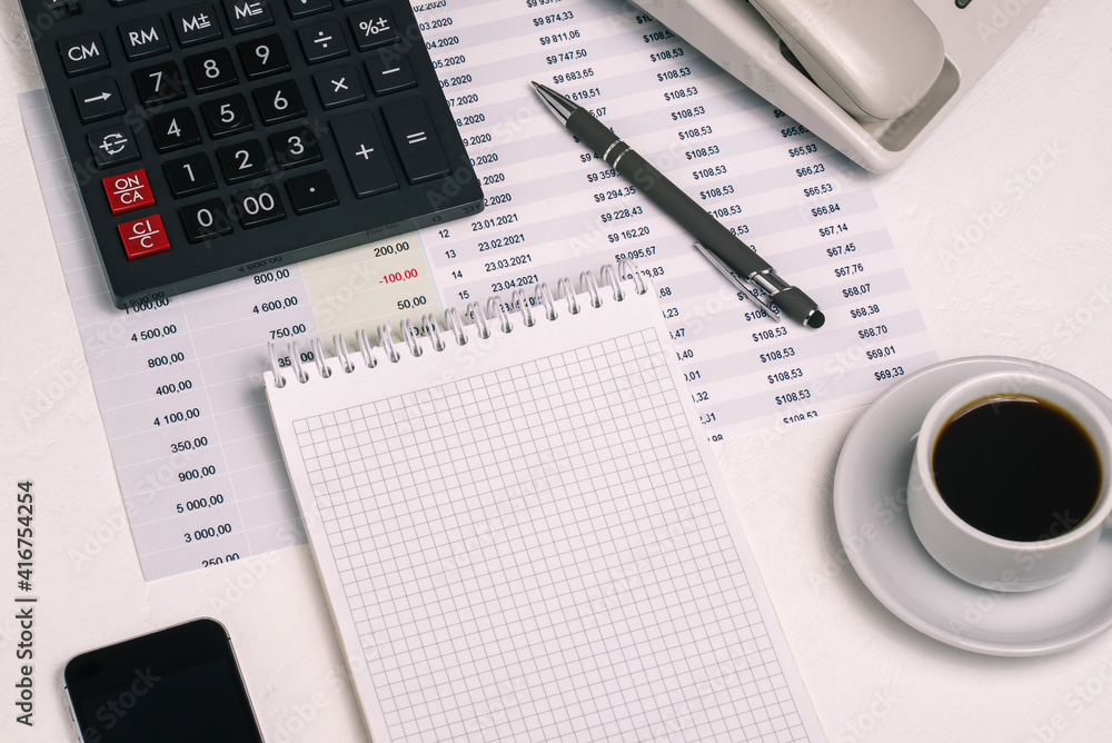 Cup of tea, an open page of an empty notebook, a phone, and a pen. Accounting and Finance. Desk of a businessman Cup of tea, an open page of an empty notebook, a phone, and a pen. Accounting and Finance. Desk of a businessman