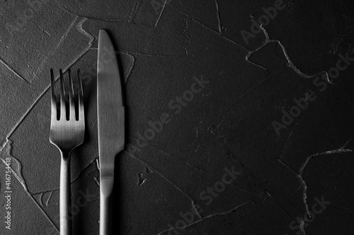 black textured background with black fork and knife