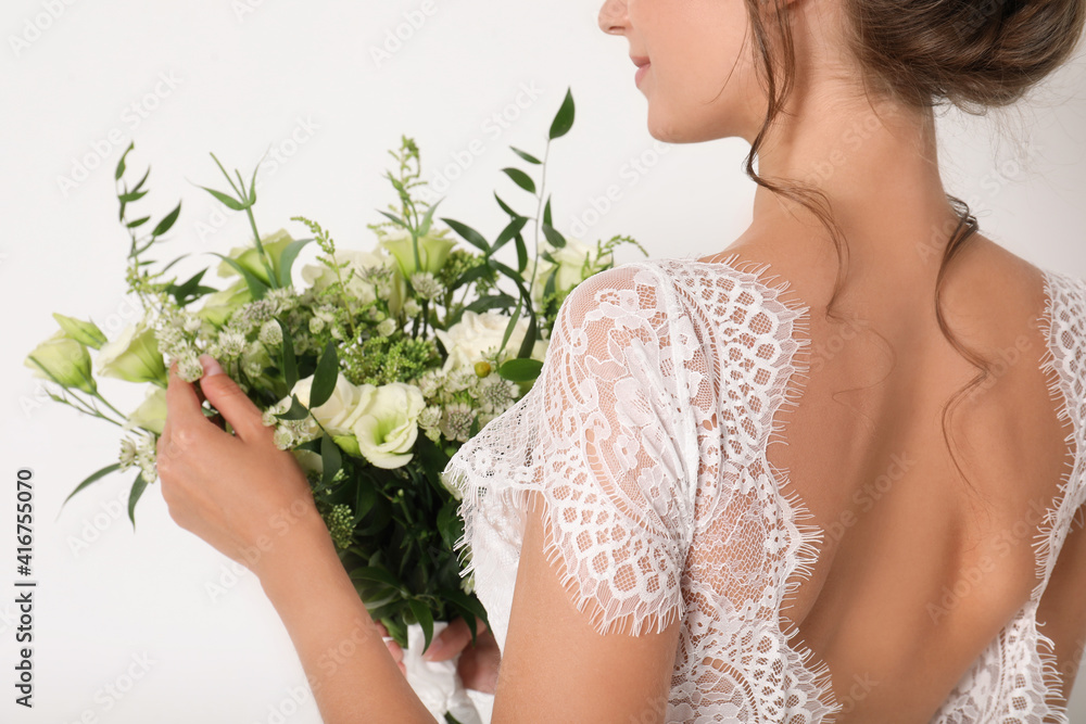 Young bride wearing wedding dress with beautiful bouquet on light background, closeup Young bride wearing wedding dress with beautiful bouquet on light background, closeup