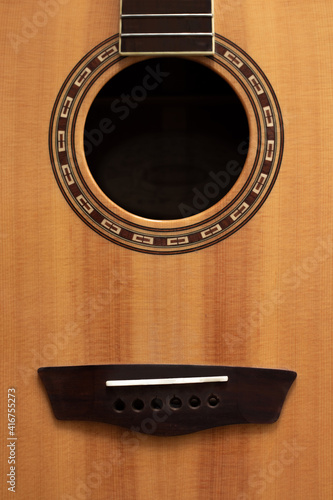old wood guitar without strings made of light wood with brown patterns and a black hole 