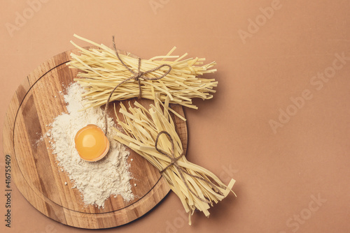 Uncooked Homemade Noodle Dried Homemade Wheat Noodles and Ingredients Flour and Eggs on Wooden Tray Top View Horizontal