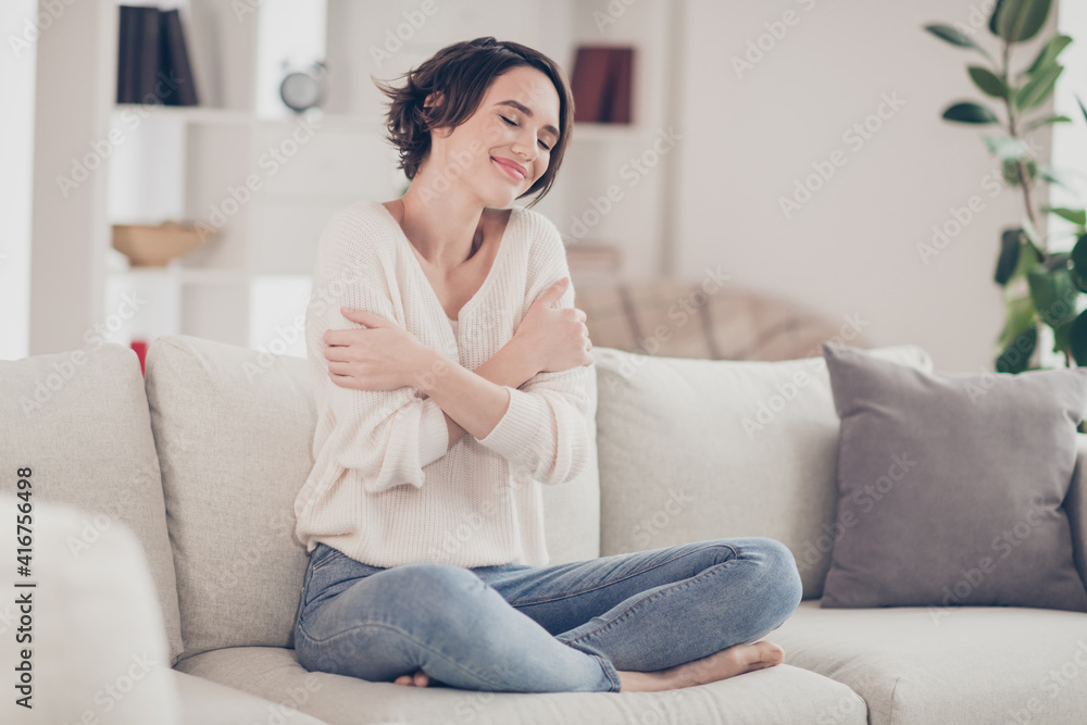 Full size portrait of pretty peaceful lady sit on sofa hands cuddle shoulder enjoy free time home indoors Full size portrait of pretty peaceful lady sit on sofa hands cuddle shoulder enjoy free time home indoors