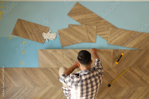 Professional worker installing new parquet flooring indoors, top view photo