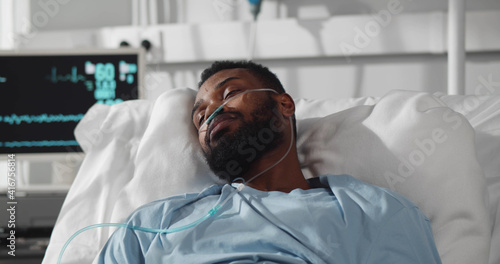 Young african man patient suffering from high fever having flu o while lying with in hospital room