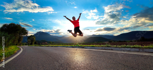 woman jumping in the road in the middle of a nature landscape