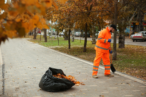 Street cleaner sweeping fallen leaves outdoors on autumn day photo