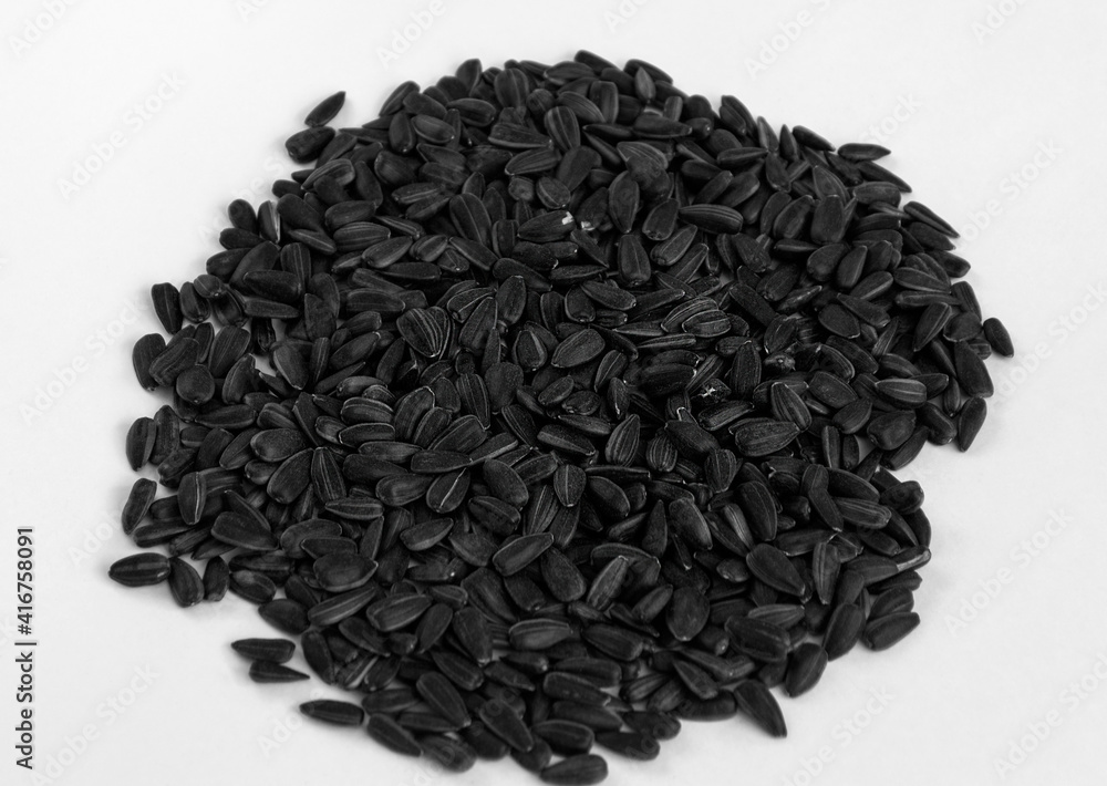 Black sunflower seeds scattered in a bunch on a white background. Black sunflower seeds scattered in a bunch on a white background.
