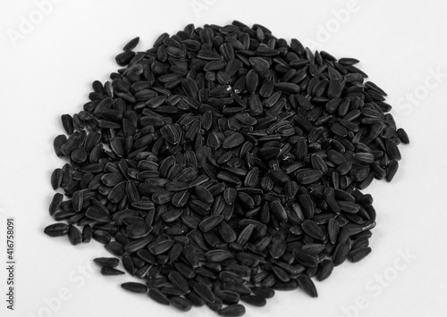 Black sunflower seeds scattered in a bunch on a white background.