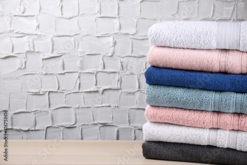 Stacked soft terry towels on wooden table. Space for text
