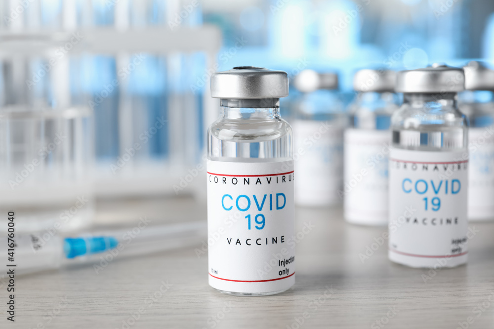 Glass vials with COVID-19 vaccine on wooden table Glass vials with COVID-19 vaccine on wooden table