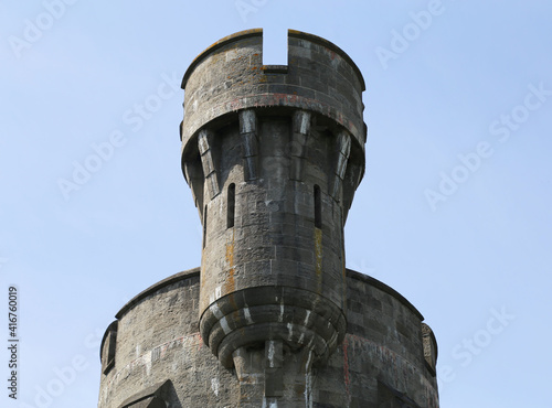 A crenellated round stone tower set against a blue sky. Fototapet