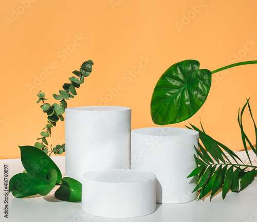 Empty cosmetics podiums on beige background with shadow and  leaves for product. 
Natural minimal beauty pedestal. 
