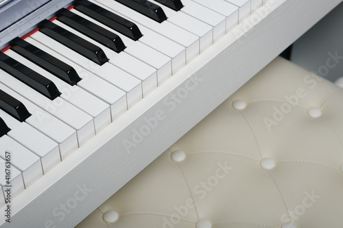 Close up of piano keyboard with blurred piano chair. Selective focus
