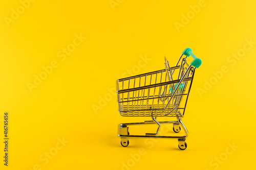 Shopping cart trolley on yellow background.
